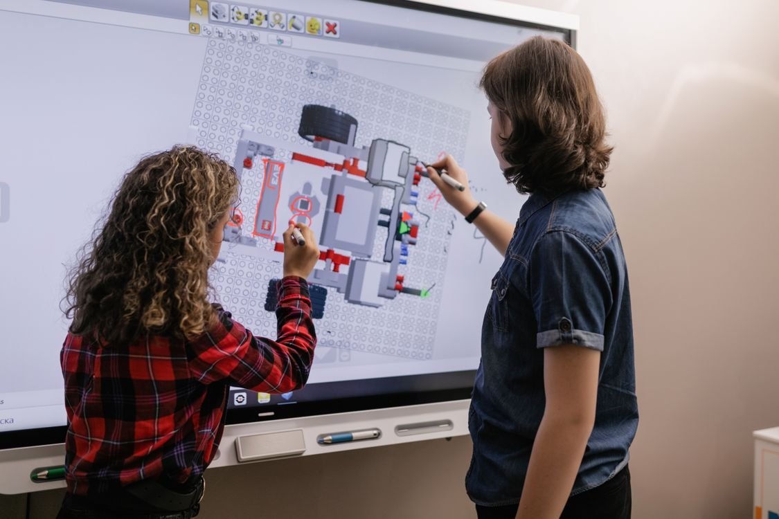 Dos escolares colaborando en una actividad con una pizarra digital interactiva en el aula